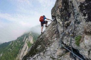 Young Man Climbing Up Cliff