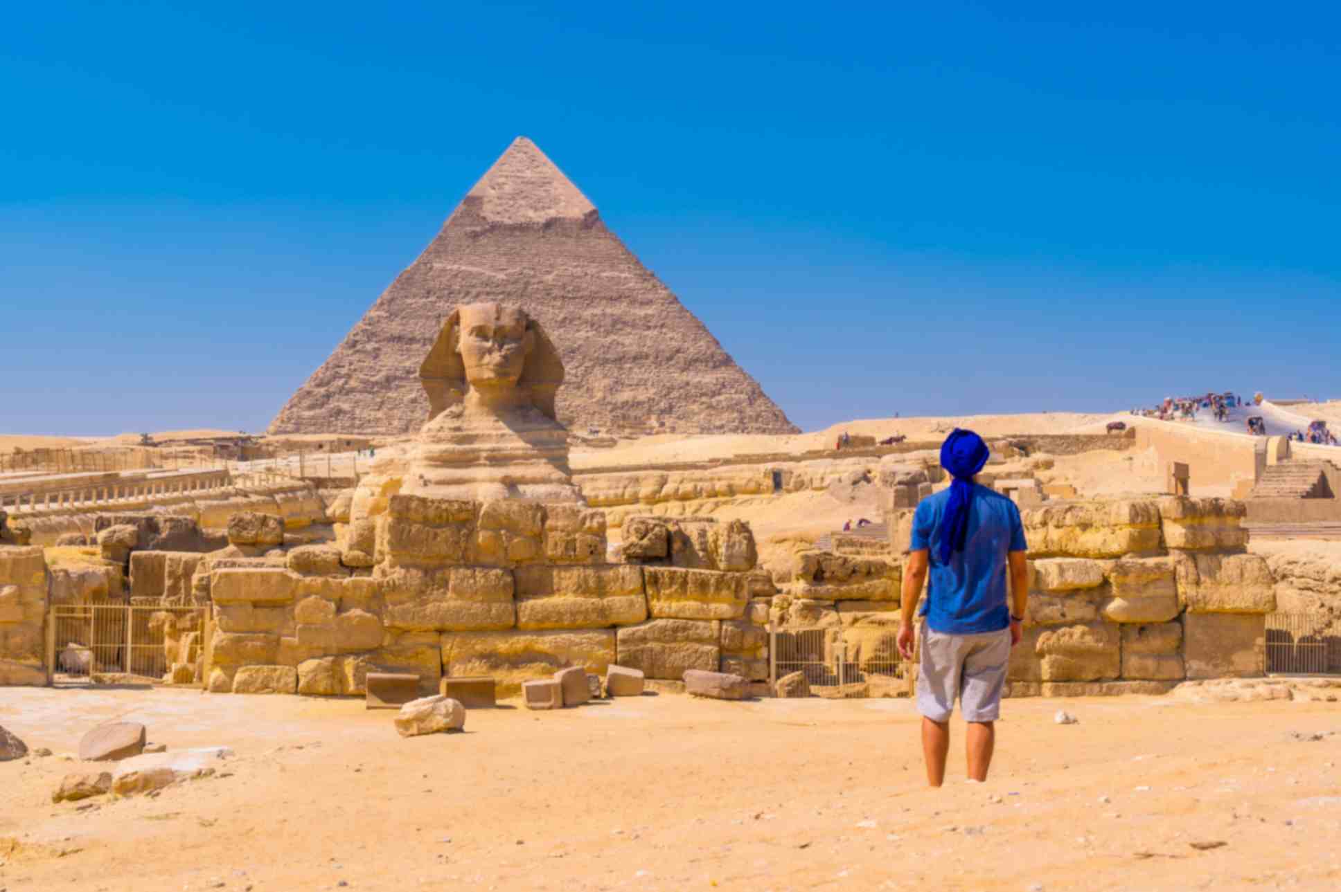 Young man walking towards great pyramids of Giza