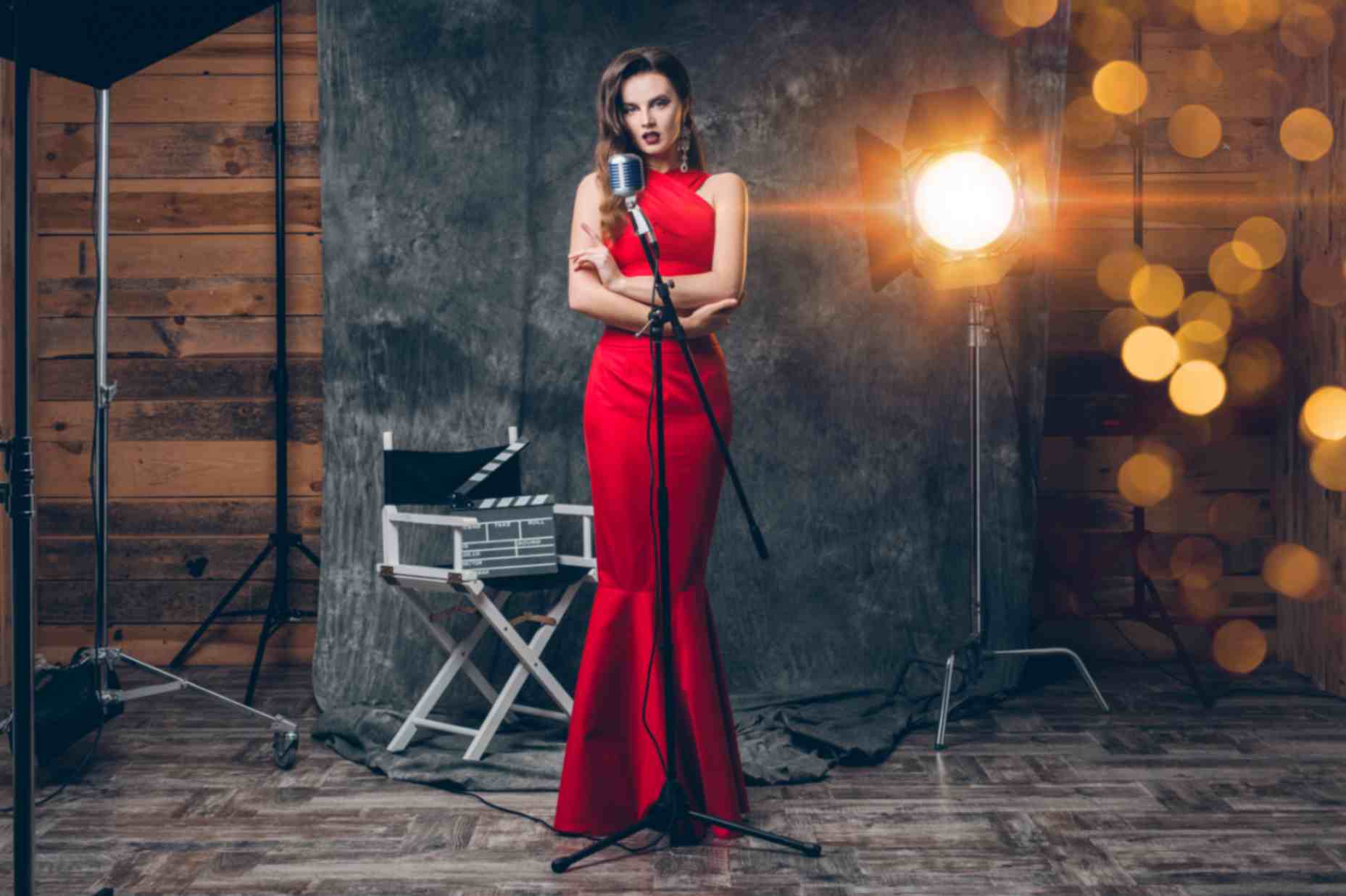Young stylish woman in cinema backstage celebrating evening wearing red dress