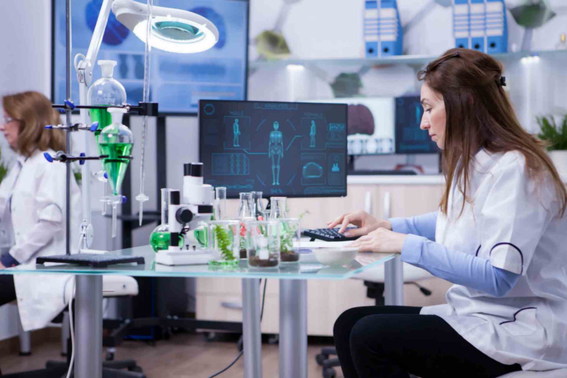 female scientist typing her computer data from last scientific tests chemistry lab