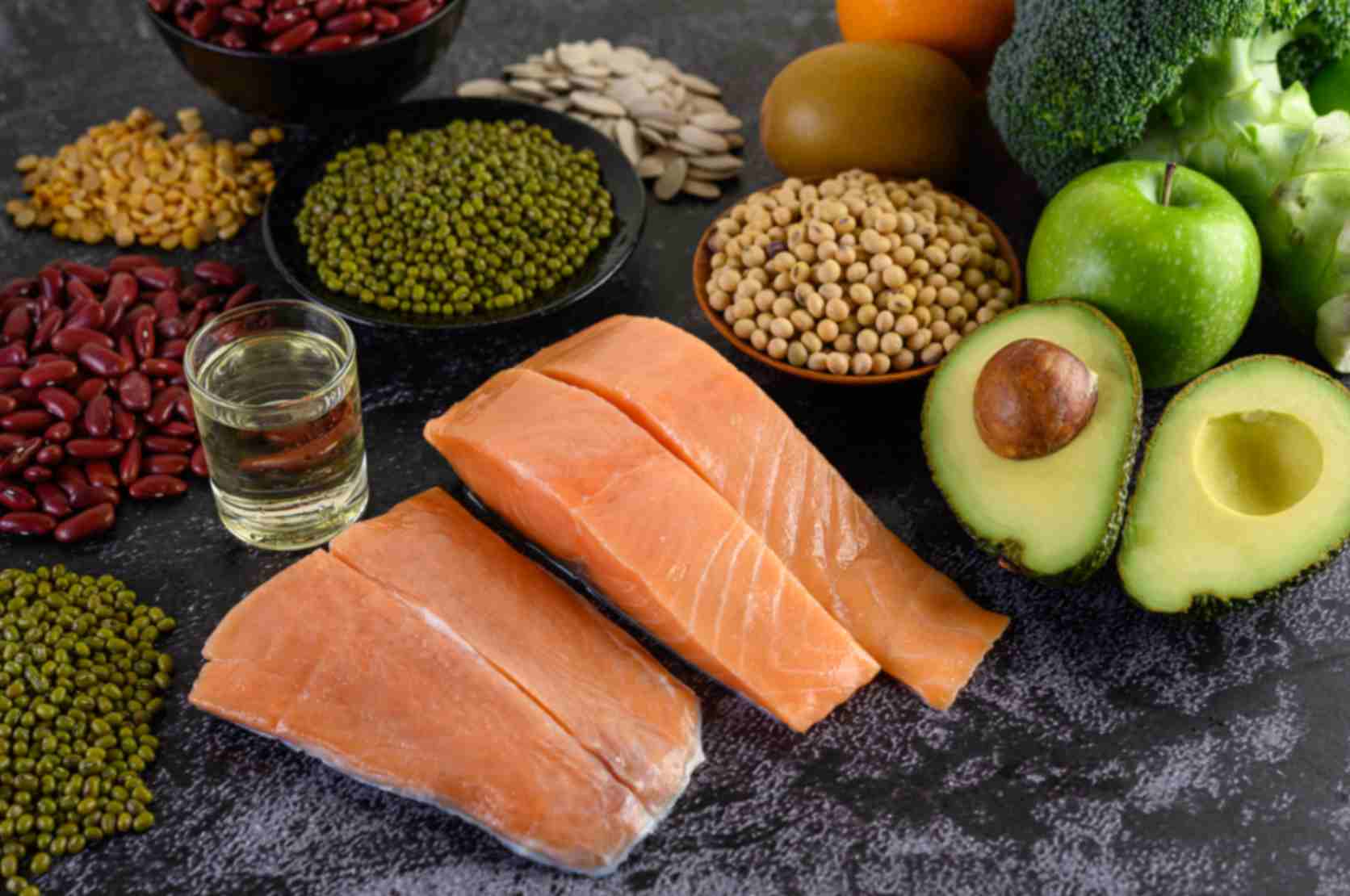 legumes, broccoli, fruit, salmon placed on black cement floor - healthy fats