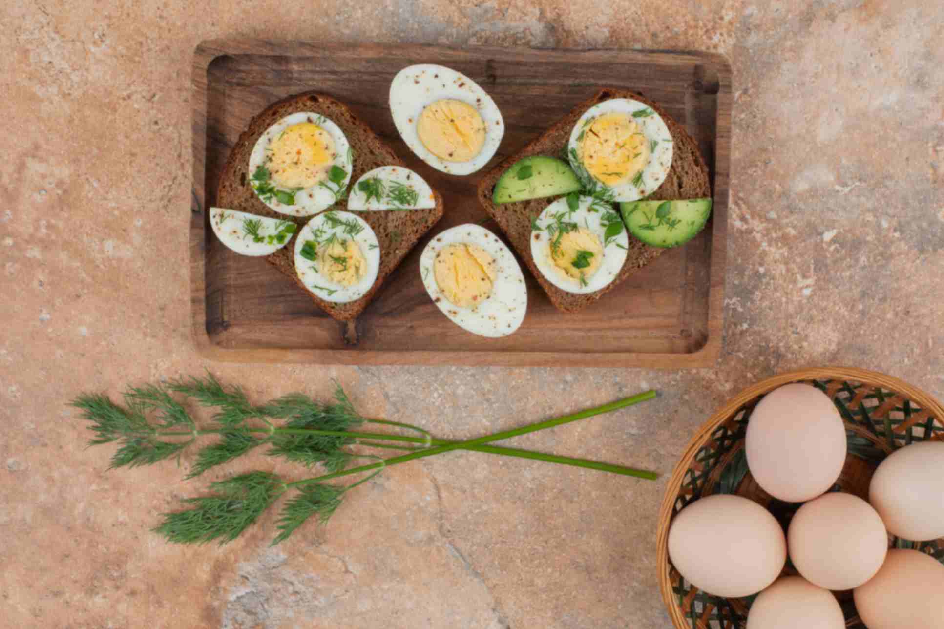 Two toasts with cucumber boiled eggs on marble table