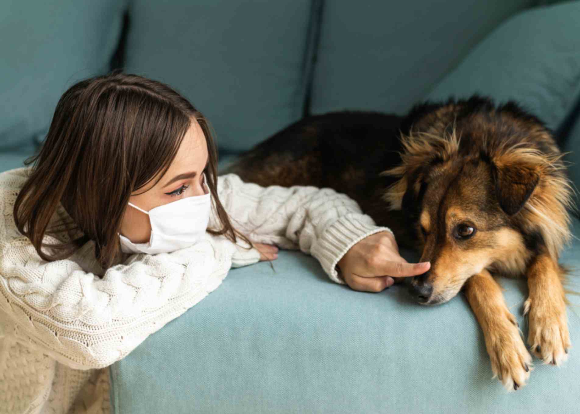 woman with medical mask sitting with her dog